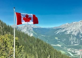 flag_of_canada_rising_over_mountain_range_covered_in_trees flag_of_canada_rising_over_mountain_range_covered_in_trees